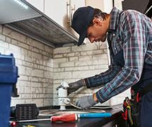 A male plumber completing plumbing services in a residential kitchen