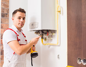 A male plumbing and drains professional standing in white and red overalls and holding a drill while completing service