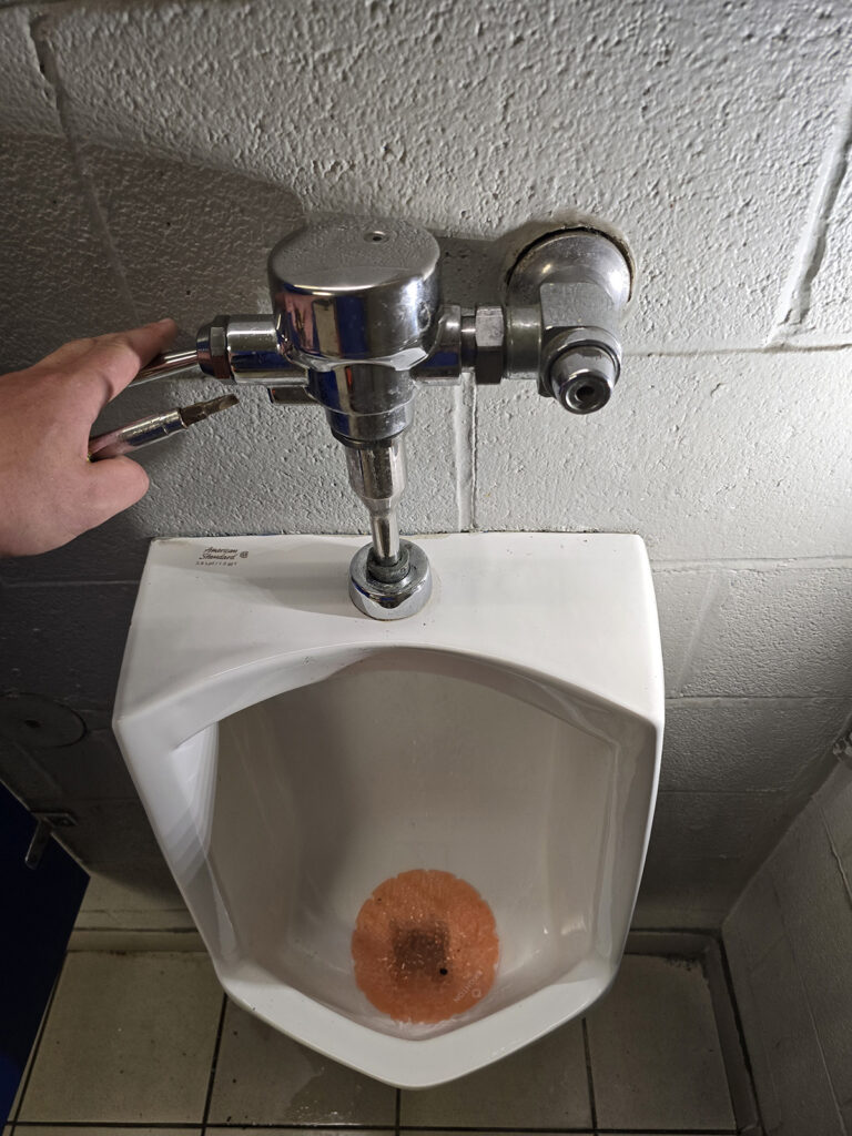 Close up of the top of a urinal as it's being repaired by a licensed Plumber from Prostream Mechanical